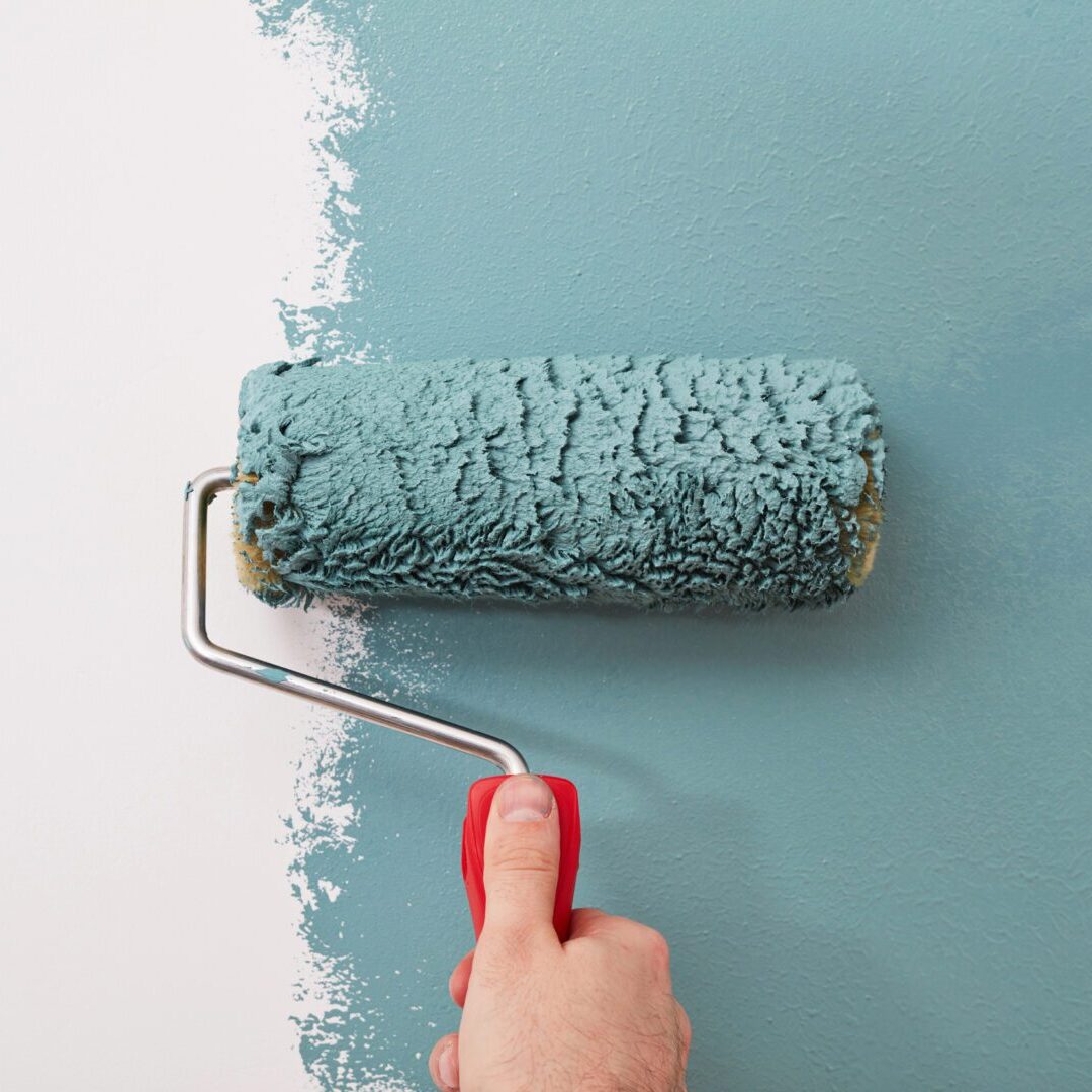 A person is painting the wall with a roller.