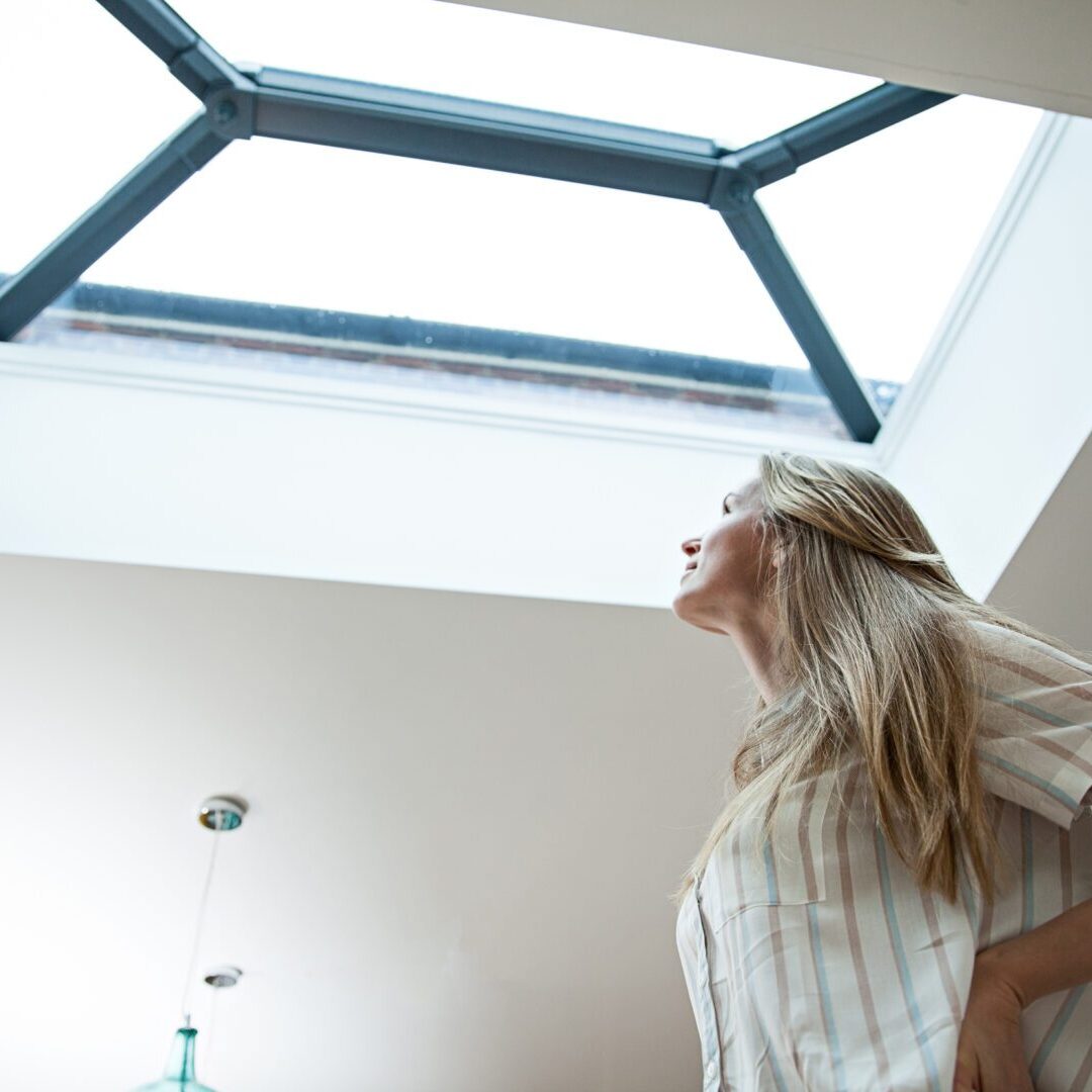 A woman standing under an open skylight.