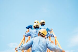 workers in blue shirts and yellow construction hats climbing stairs